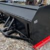A black and red plow is sitting on the ground