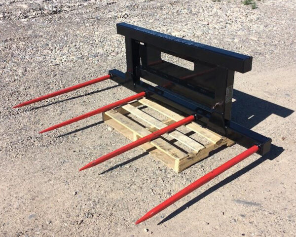 A black metal frame with six red prongs resting on a wooden pallet outdoors.