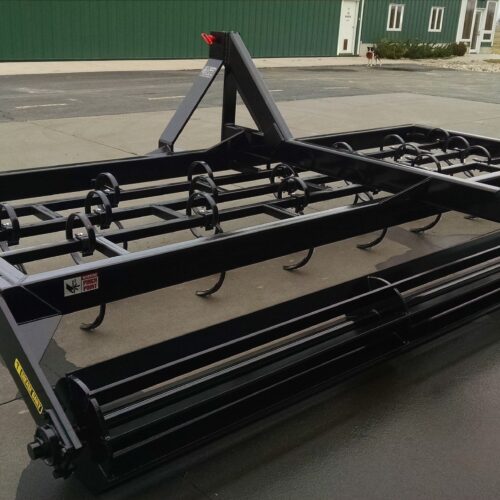 A black metal plow sitting on top of the ground.