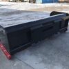 A black truck bed sitting on top of concrete.