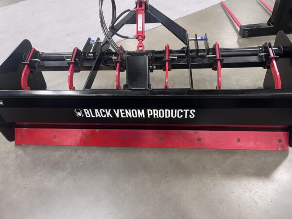 A red agricultural implement labeled 'Black Venom Products' with hydraulic hoses.