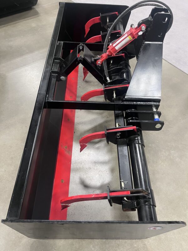 Close-up of a red and black snow plow attachment on a concrete floor.