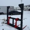 Heavy-duty metal frame with red clamps on snowy ground near trucks.