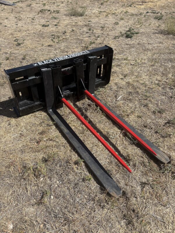 Heavy-duty hay bale spear attachment with three long tines.