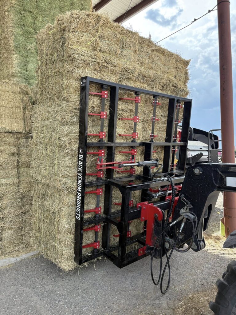 A machine stacking large bales of hay outdoors.